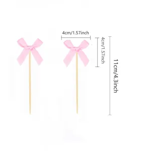 Close-up view of pink fabric bow cupcake toppers with wooden sticks for party decoration.