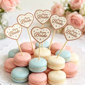 Dettaglio topper per cupcake a cuore team sposa con macaron colorati e sfondo floreale.