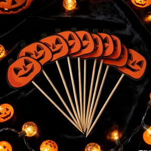 Detailed shot of Halloween pumpkin cupcake toppers on wooden sticks with glowing fairy lights.