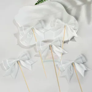 White bow cake topper detail view, elegant ribbon dessert decoration for party baking.