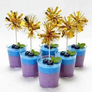 Close-up detail of shiny gold tinsel firework picks inserted in layered dessert cups.