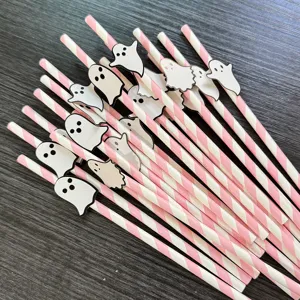 Close-up detail of Halloween pink striped paper straws with cute ghost decorations for party.