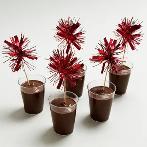 Detailed shot of red tinsel firework cake picks and plastic dessert cups for festive party decor.