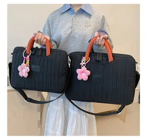 Detailed view of black pleated tote bag with orange handle and cute flower pendant.