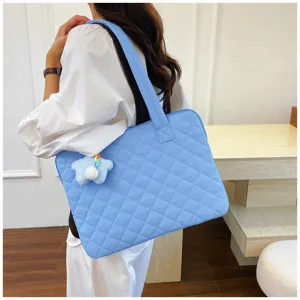 Detail view of light blue quilted laptop bag with cute star pendant for women commuting.