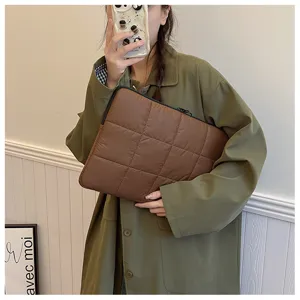 Detailed view of the brown quilted laptop sleeve showing soft puffer texture and zipper closure.