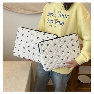 Vista dettagliata della custodia trapuntata bianca per laptop con fiocco nero, borsa morbida.