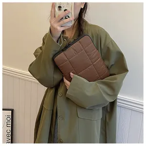 Detailed view of brown quilted laptop sleeve, soft down-like texture, dual zipper design.