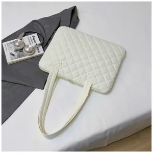 Detail view of the quilted white laptop bag, showing soft padded texture and sturdy handles.