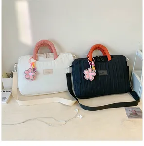 Details of trendy pleated puffer laptop tote bag with cute flower charm and contrast handle.