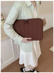 Detailed view of brown quilted laptop sleeve, minimalist striped padded computer pouch.