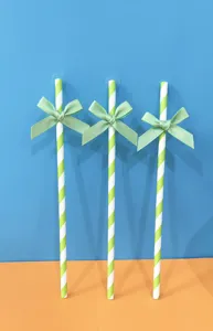 Dettaglio di paglia di carta a righe con fiocco verde, ideale per feste e compleanni.