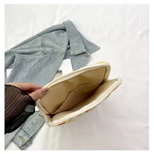 Vista dettagliata della custodia per tablet crema con tasca con zip e supporto in denim.