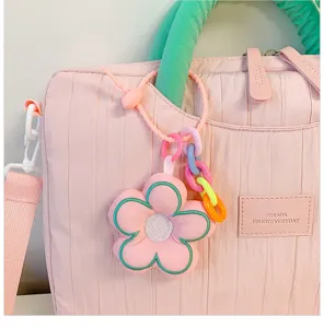 Close-up detail of pink quilted laptop tote bag featuring green handle and cute flower charm.