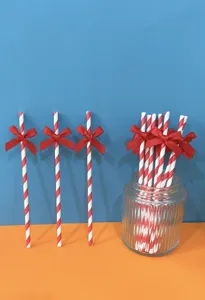 Cannucce di carta a righe rosse e bianche con fiocco rosso per decorazioni di feste.