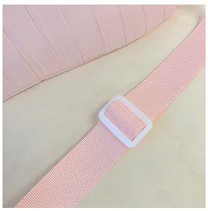 Close-up detail of the pink pleated tote bag strap with white buckle on wooden background.