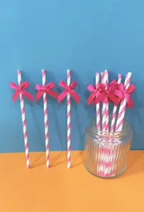 Vista dettagliata di cannucce di carta a righe rosa e bianche con fiocchi per le feste.
