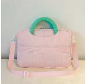 Detailed view of pink laptop shoulder bag featuring green handle and vertical texture.