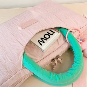 Pink textured tote bag detail view, showing pleated fabric, front pocket and green handle.