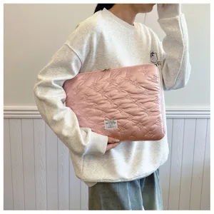 Close-up view of the pink quilted laptop sleeve with cute bow pattern and woven label.