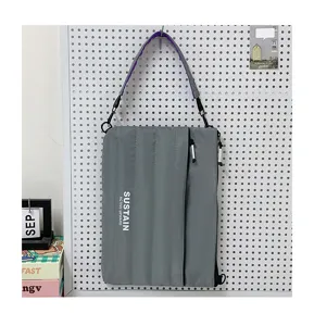 Detailansicht der grauen 14-Zoll Laptop-Umhängetasche an Lochwand mit Textaufdruck.