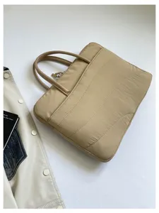Detailed view of beige quilted laptop bag featuring soft shockproof fabric and dual handles.