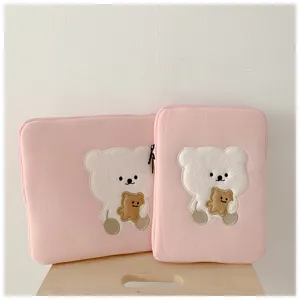 Close-up detail of cute bear embroidery laptop sleeve, soft pink plush fabric design.