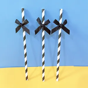Cannucce di carta a righe bianche e nere con fiocco nero per decorazioni di feste e tavoli da dessert.