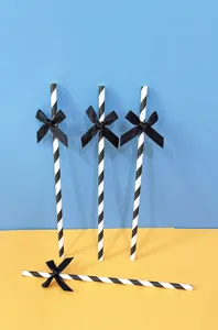 Cannucce di carta a righe bianche e nere con fiocchi neri per decorazione tavolo festa dettaglio.