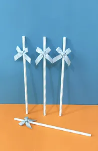 Primo piano ravvicinato e dettagliato di cannucce di carta a righe blu decorate con fiocco.