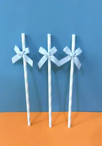 Primo piano di cannucce di carta a righe blu e bianche decorate con fiocchi per feste.