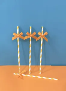 Cannucce di carta a righe gialle e bianche con fiocco arancione per feste e decorazione.