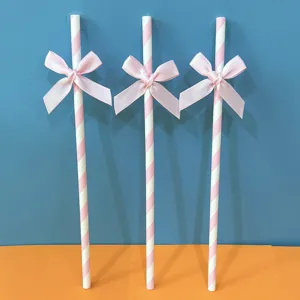 Dettaglio di cannucce di carta a righe rosa con grazioso fiocco, ideali per feste e tavoli da dessert.