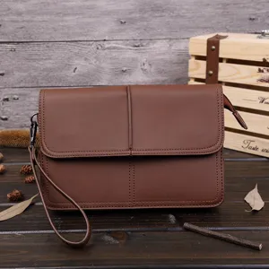 Bolso de mano marron para hombre en detalle, cartera vintage con cierre de cremallera.