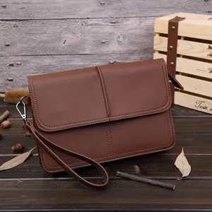 Vista detallada del bolso de mano vintage marrón para hombre con correa en madera rústica.