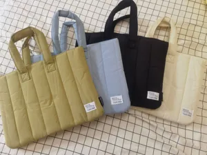 Detailed view of padded laptop tote bag showing quilted texture, durable handles and woven label.