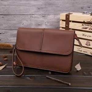 Detalle de bolso de mano de cuero marrón para hombre, cartera vintage con correa.
