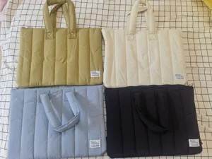 Detail view of quilted laptop tote bag showing four color options with carry handles.