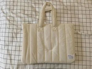 Quilted laptop bag detail showing soft padded fabric, dual handles and woven label.