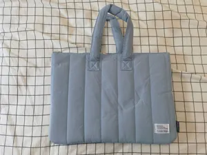 Light blue quilted laptop bag with dual handles and zipper closure, perfect for daily use.