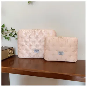 Close-up detail of quilted bow embroidered laptop sleeve set showcased on a wooden desk.
