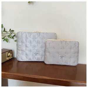 Detail view of grey quilted laptop sleeve with cute white bow embroidery and double zippers.