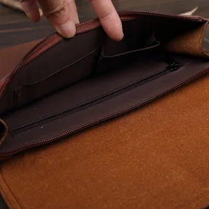 Bolso de mano vintage de cuero marrón para hombre con múltiples compartimentos y bolsillos.
