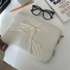 Nahaufnahme des gesteppten weißen Laptoptaschen-Details mit süßer Schleife und Metallreißverschluss.