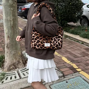Elegante borsa per laptop in peluche leopardato, consistenza morbida, pratica borsa a mano chic.