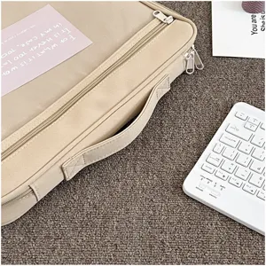 Detalle de funda para portátil beige de lona, doble cremallera resistente, asa práctica.