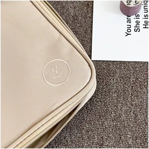 Detalle de funda para laptop minimalista, bonita bolsa beige para tableta con carita bordada.