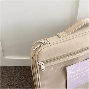 Detalle de funda para portátil beige minimalista con cremalleras dobles y asa resistente.