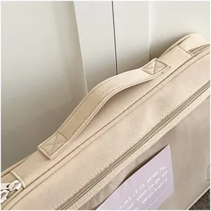 Primer plano detallado de la funda para portátil beige con asa resistente y cremallera suave.