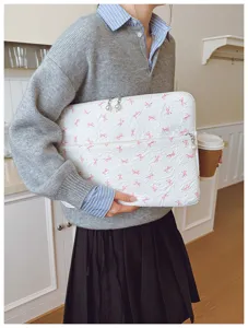 Housse d'ordinateur matelassée chic avec nœuds roses et fermeture éclair perlée élégante.